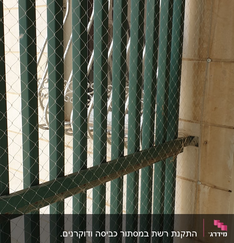 רשת מתוחה על סורגים ירוקים למניעת כניסת יונים